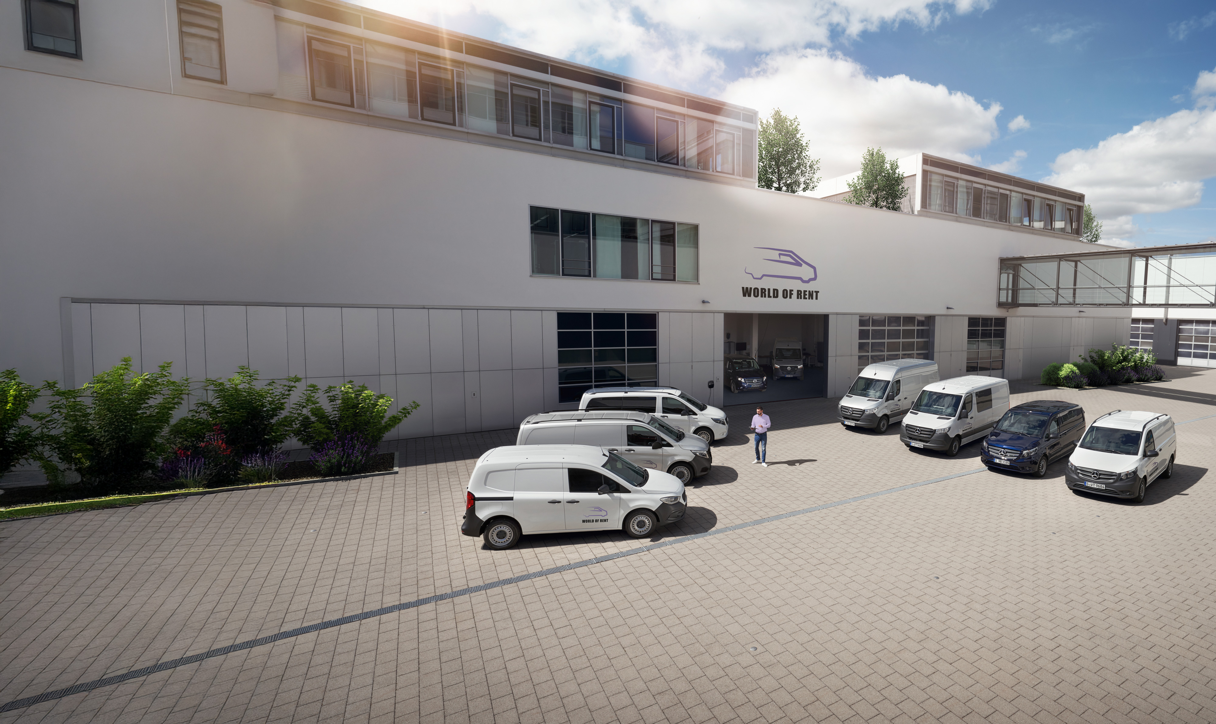 Fleet Services | Mercedes-Benz Transporter. Eine große Flotte steht auf einem sonnenbeschienenen Parkplatz vor einem Mercedes-Benz Gebäude.