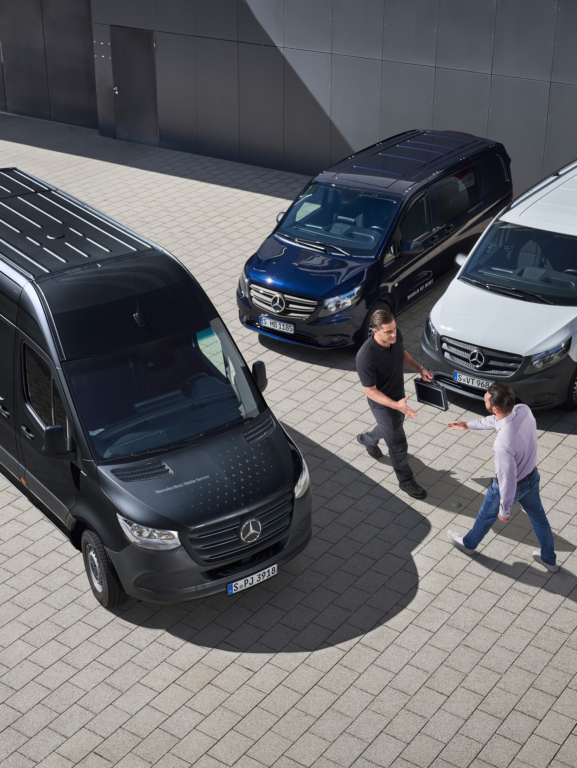 Zwei Männer begrüßen sich zwischen Mercedes-Benz Transportern – effizienter Nutzfahrzeuge Service für Flottenkunden.