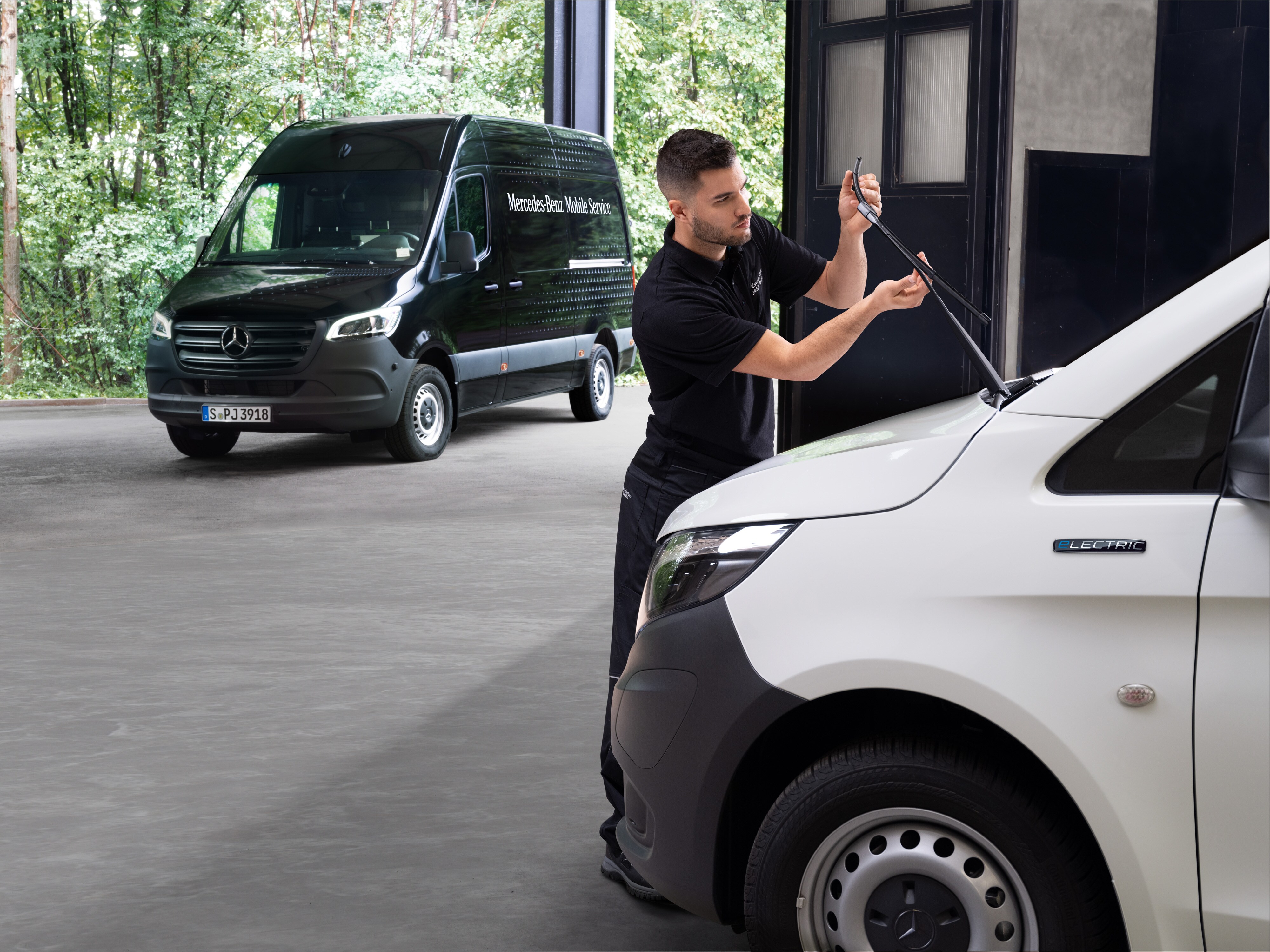 Ein Techniker wechselt die Wischerblätter an einem weißen Mercedes-Benz Vito Transporter.