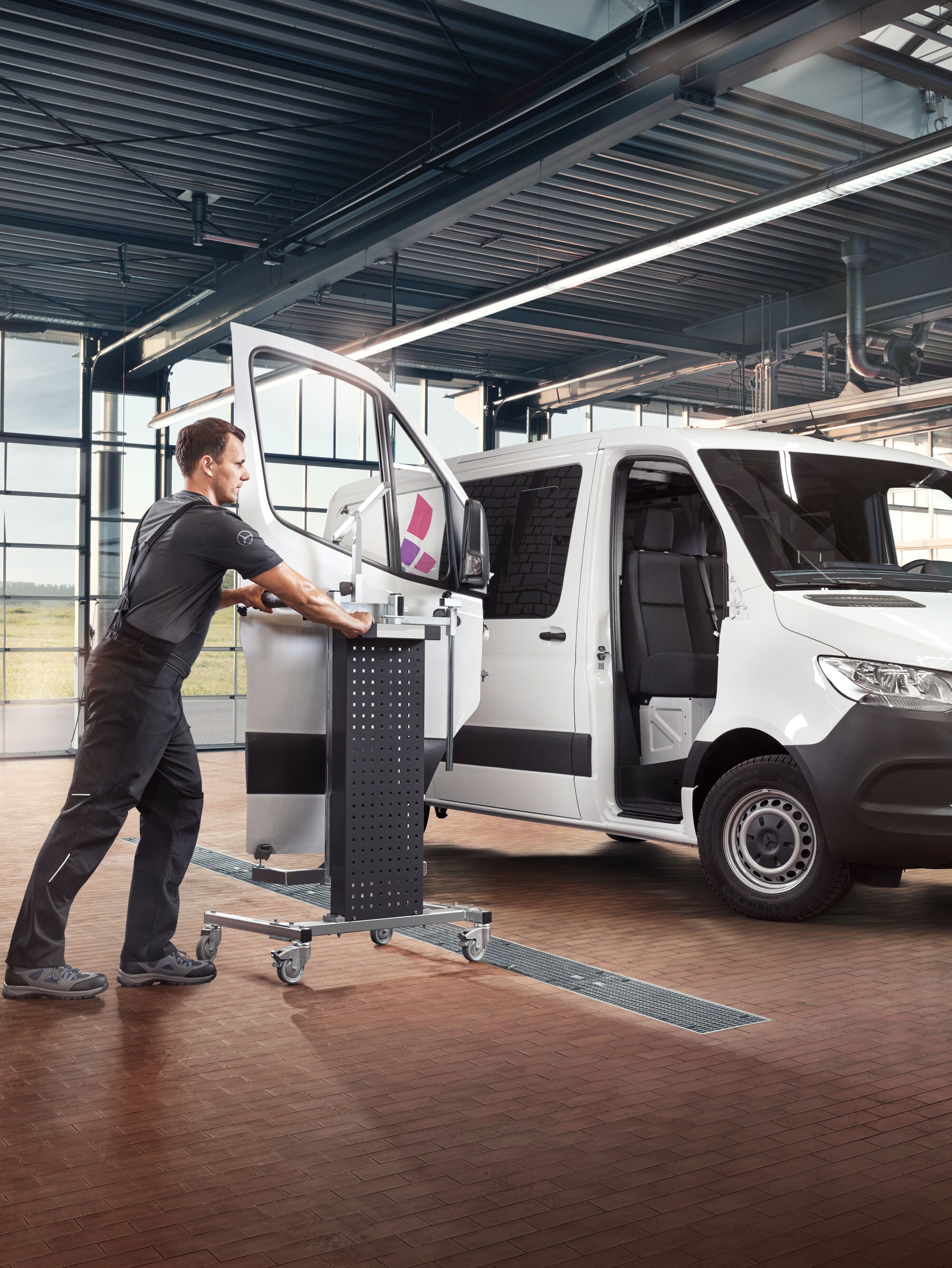 Mechaniker bei der Montage der Sprinter-Tür – zuverlässige Karosseriereparatur bei Mercedes-Benz. 