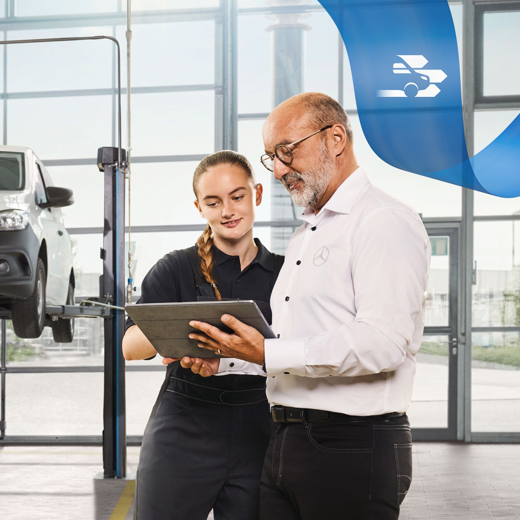 Zwei Mitarbeitende besprechen den Nutzfahrzeuge-Service an einem aufgebockten Mercedes-Benz Transporter in der Werkstatt.