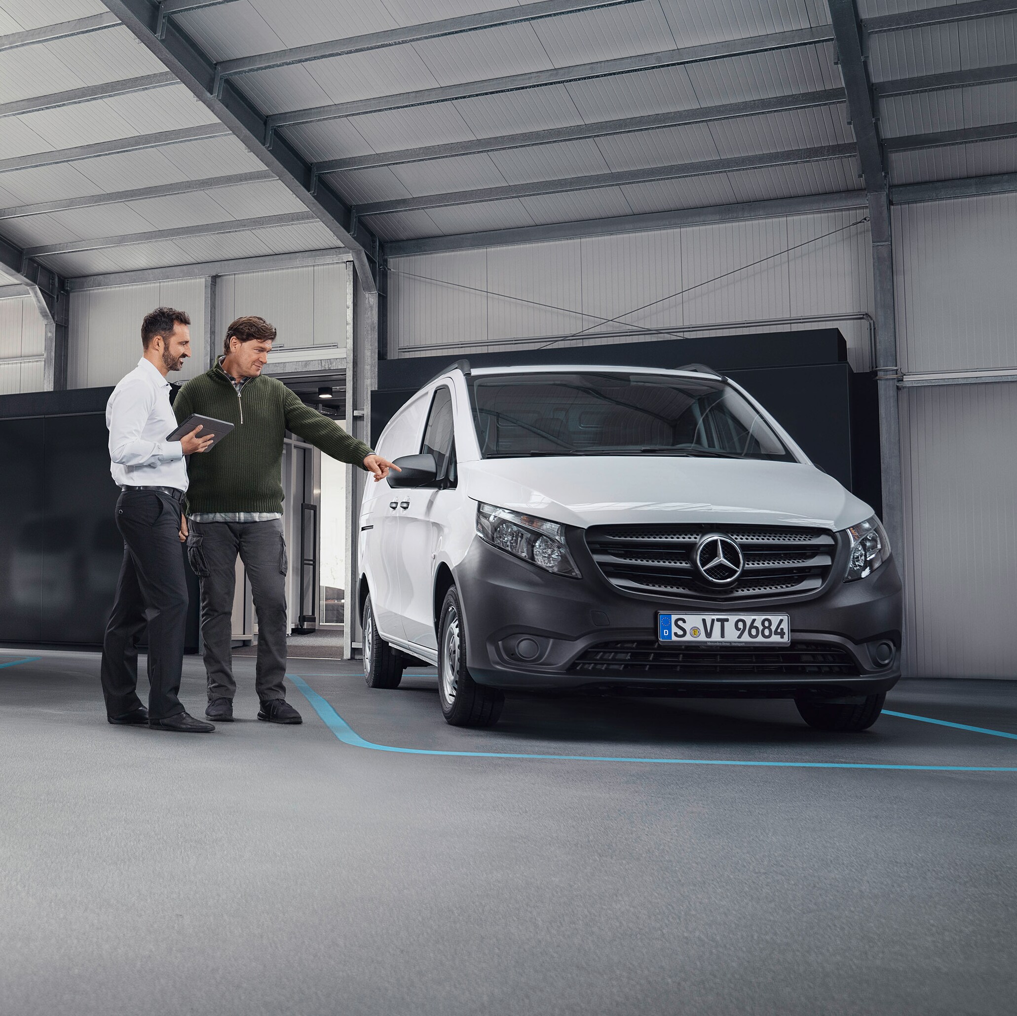 Mercedes-Benz Kundenbetreuer mit Kunde im Betrieb eines Servicepartners vor einem Transporter.