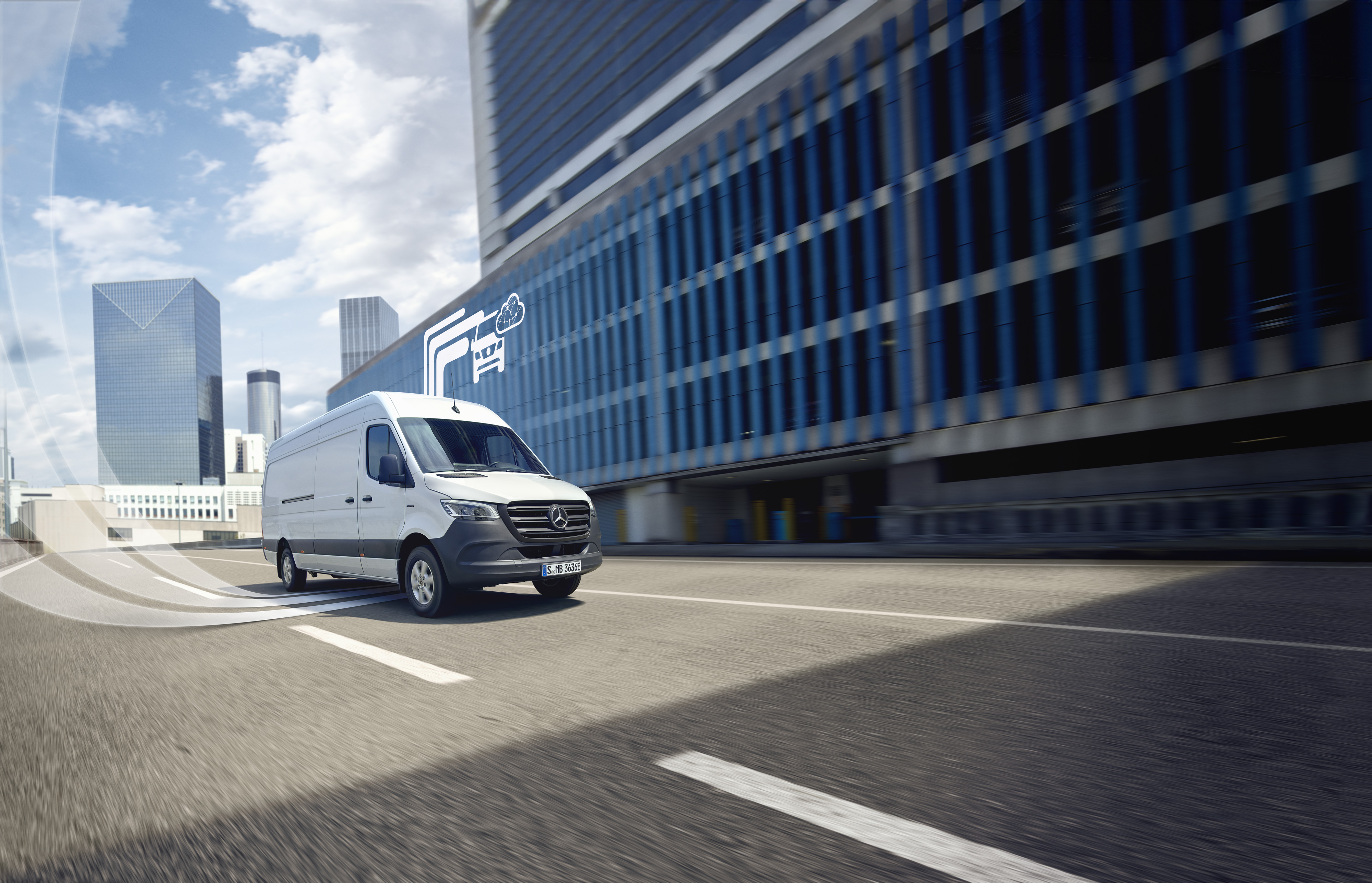 Digitale Extras | Mercedes-Benz Transporter. Weißer Mercedes-Benz Transporter fährt durch die Stadt, digitales Symbol für Mercedes-Benz Technologie im Hintergrund.