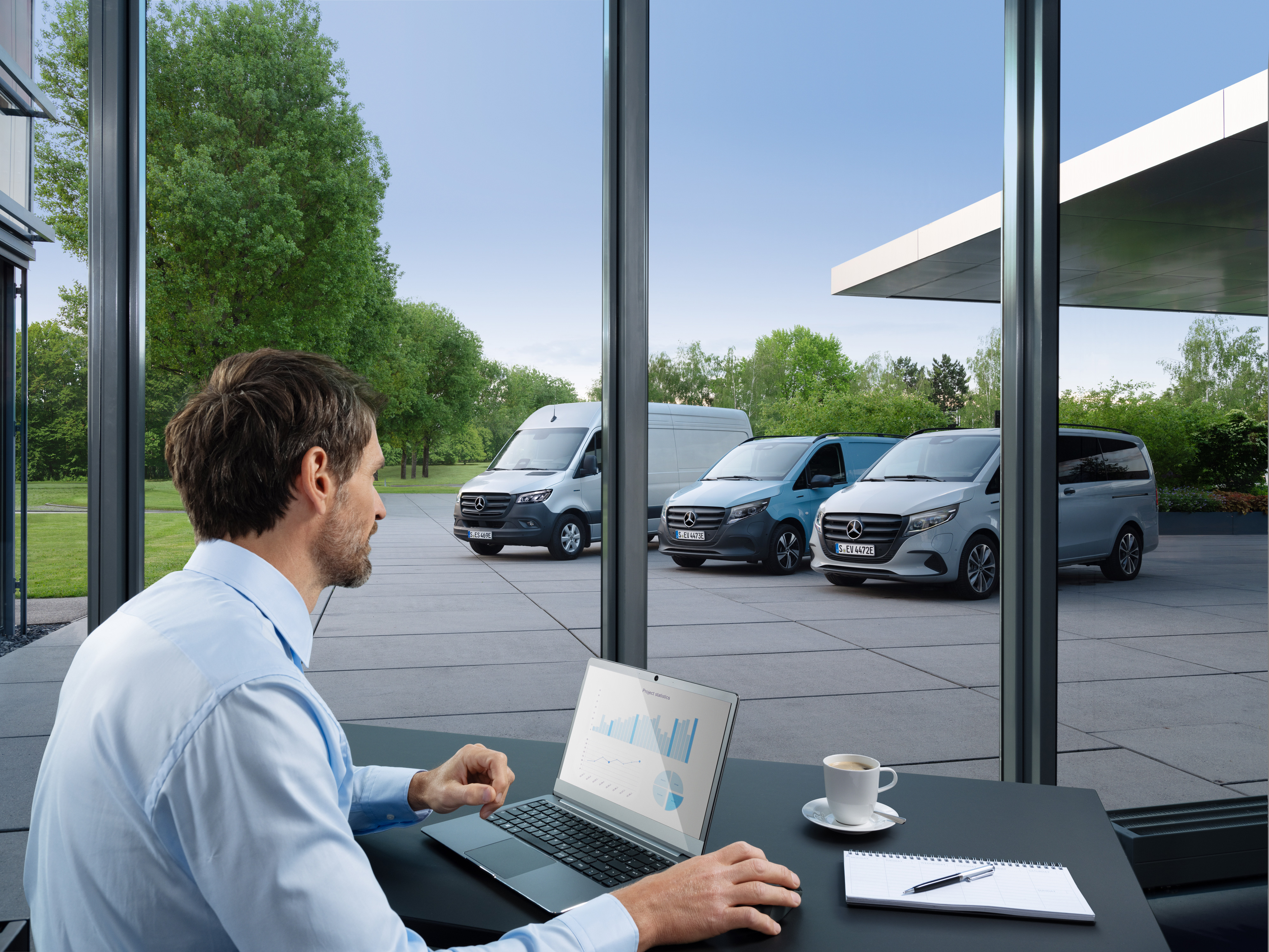 Van Uptime Monitor | Mercedes-Benz Transporter. Ein Mann überwacht mehrere geparkte Mercedes-Benz Transporter mit einem Laptop, Symbol für digitales Fuhrparkmanagement.