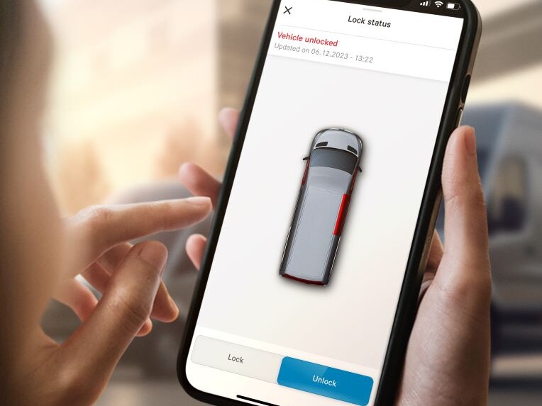 Eine Person hält ein Handy auf dem ein Fahrzeug in einer App von Mercedes-Benz angezeigt wird.