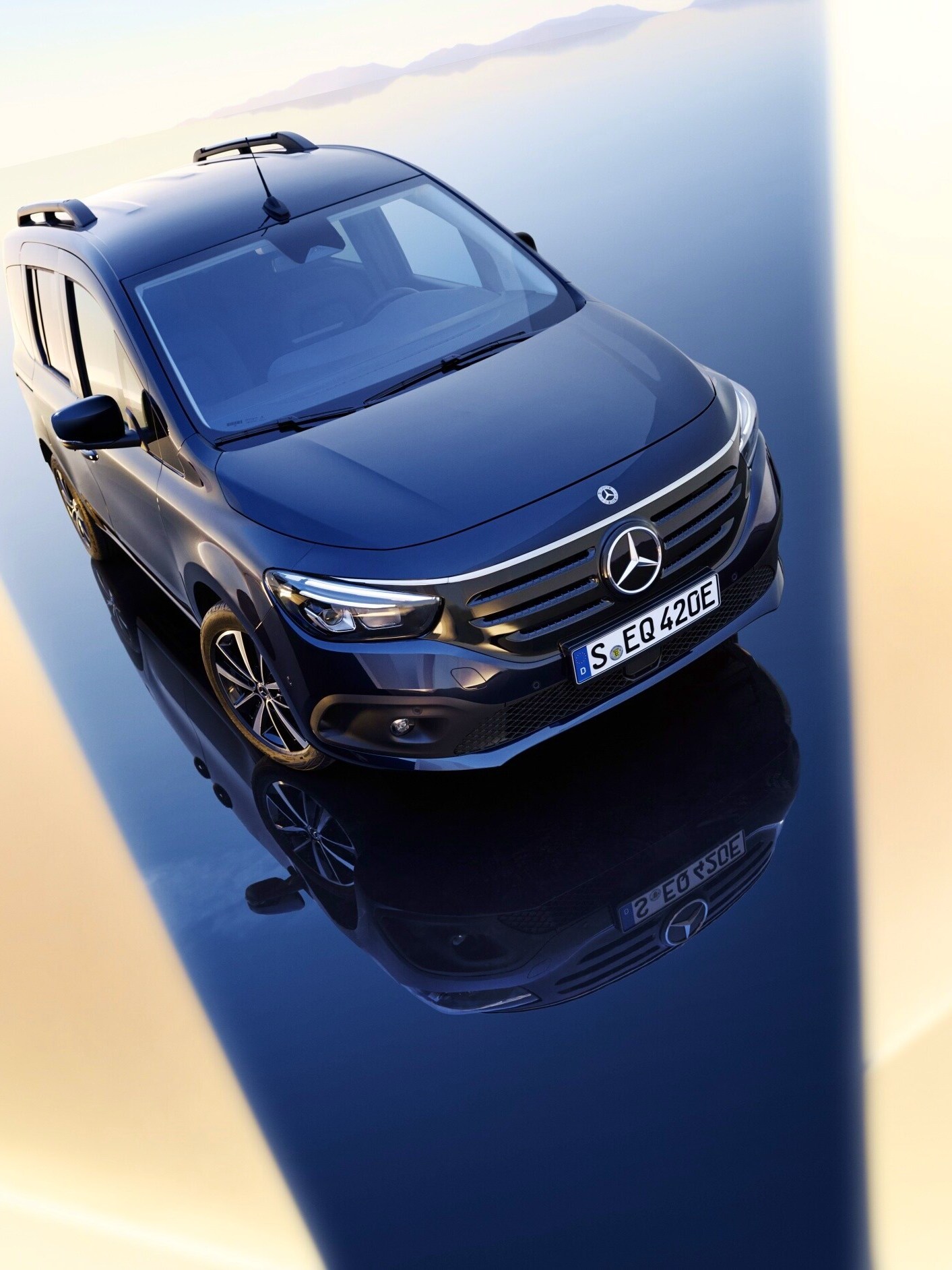 Ein dunkler Mercedes-Benz EQT auf einer spiegelnden Oberfläche im Gegenlicht.