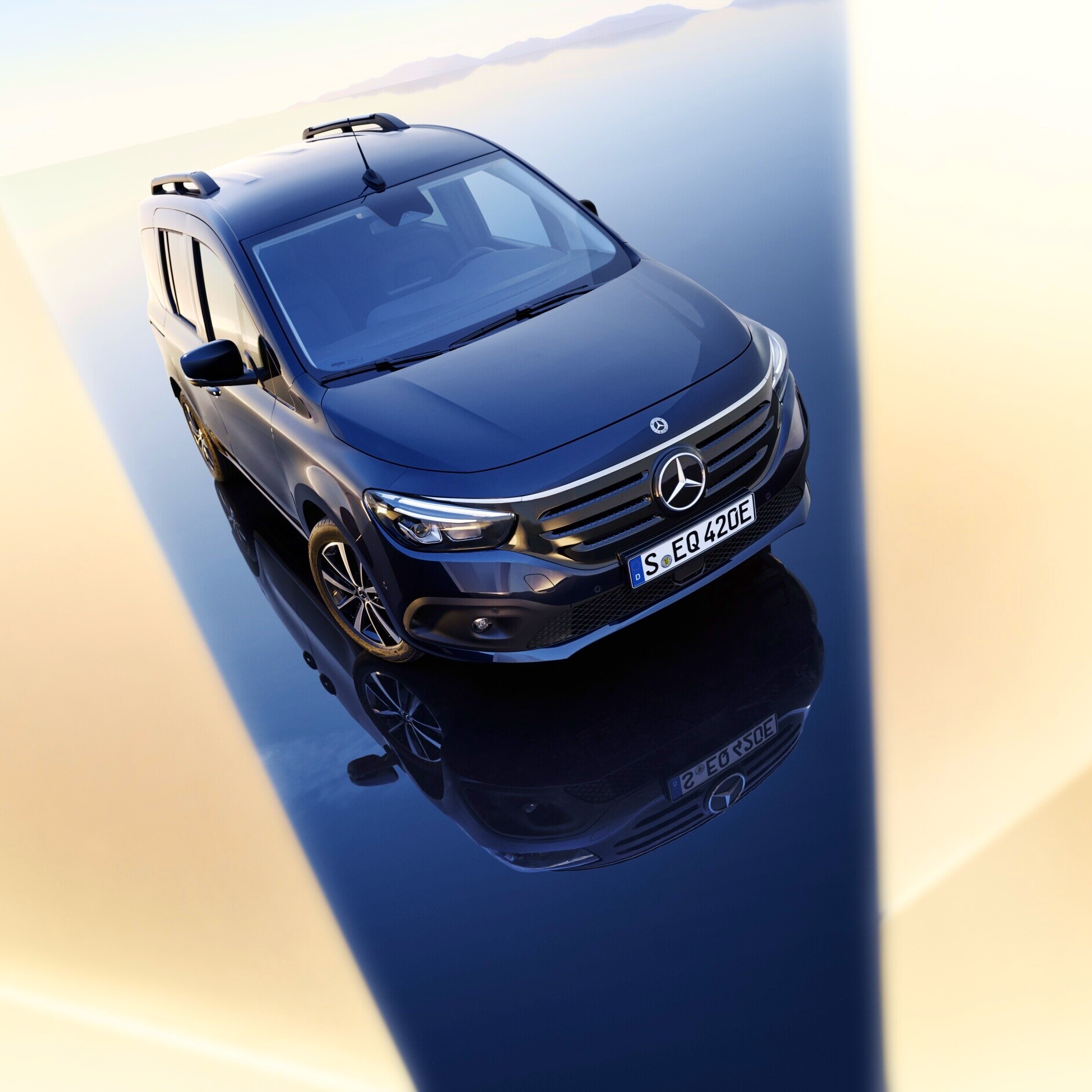 Transporter mit Elektroantrieb | Mercedes-Benz Ein dunkler Mercedes-Benz EQT auf einer spiegelnden Oberfläche im Gegenlicht.