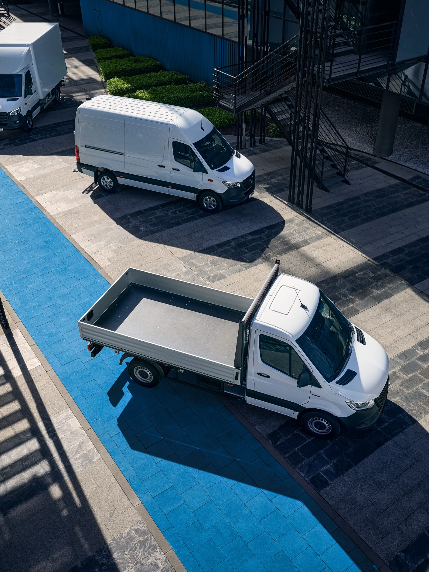 Drei Mercedes-Benz eSprinter Modelle auf einem Parkplatz mit einer blauen Markierung.