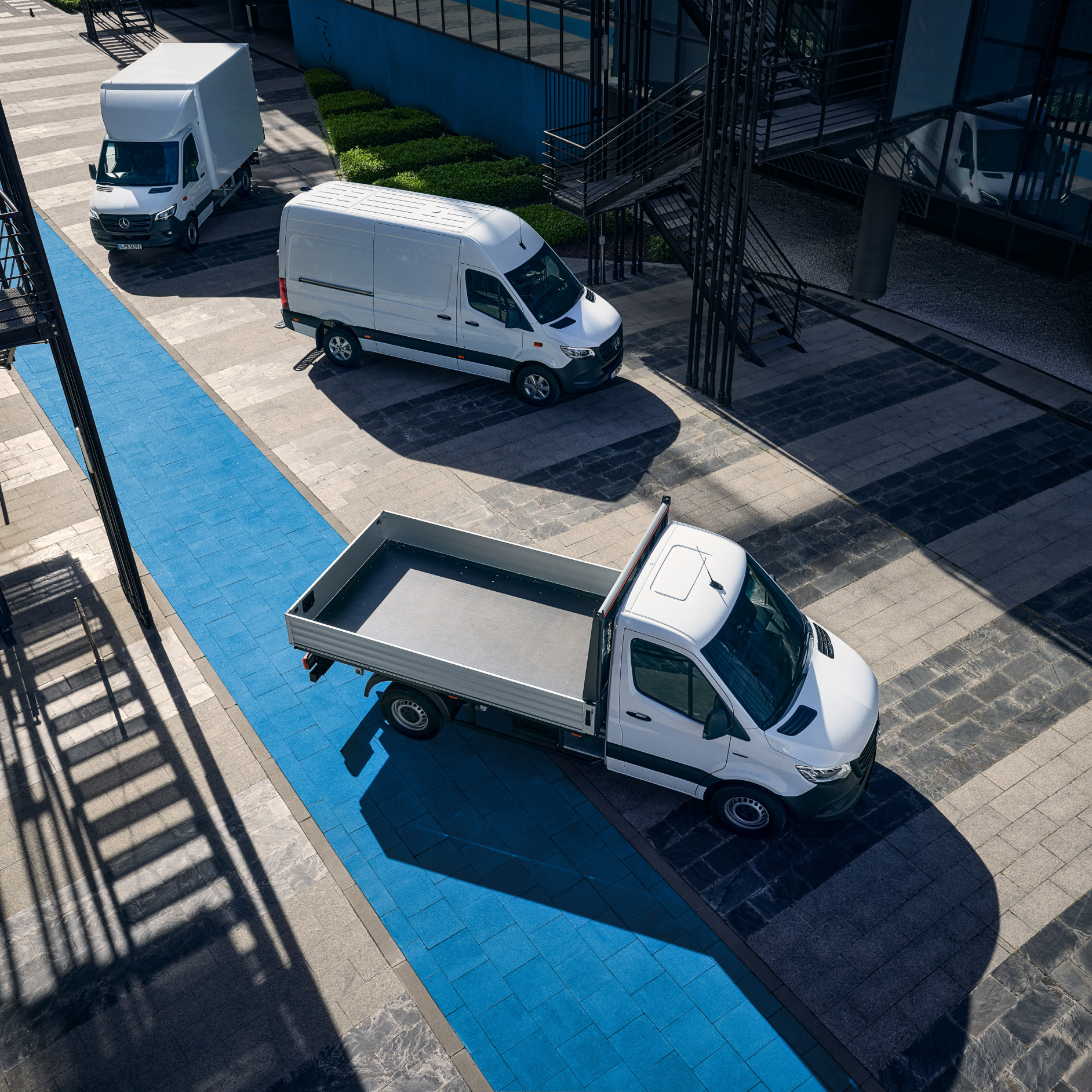 Transporter mit Elektroantrieb | Mercedes-Benz Drei Mercedes-Benz eSprinter Modelle auf einem Parkplatz mit einer blauen Markierung.