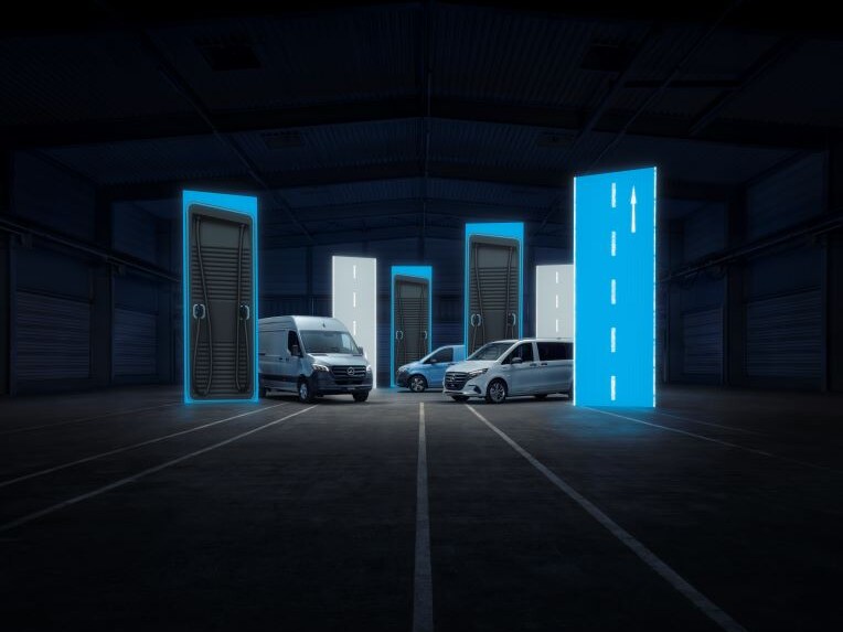 Drei Transporter von Mercedes-Benz auf einer Straße vor leuchtenden Tafeln und abgedunkeltem Hintergrund.
