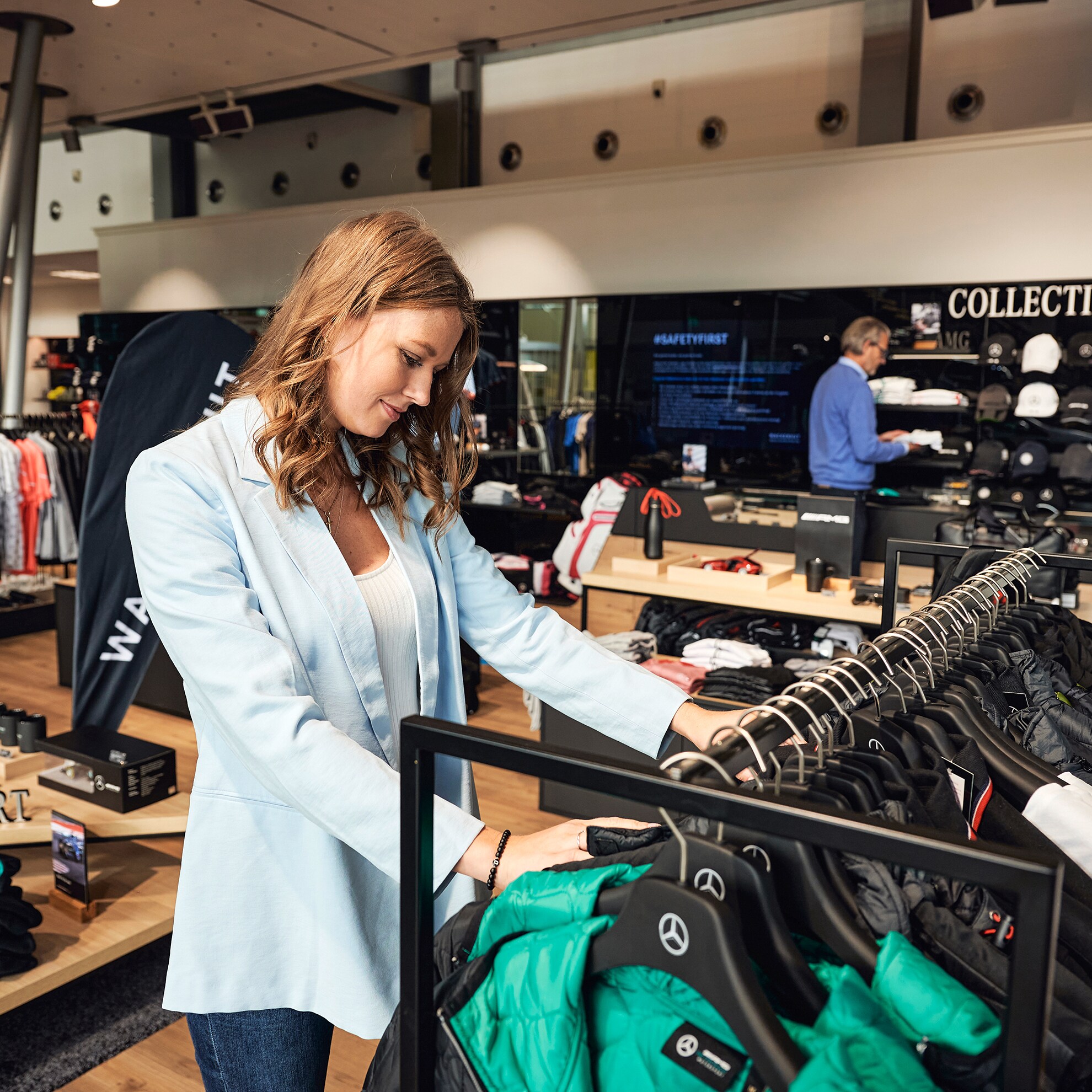 Eine Frau schaut sich Kleidung der Mercedes-Benz Collection in einem Kundencenter Shop an.