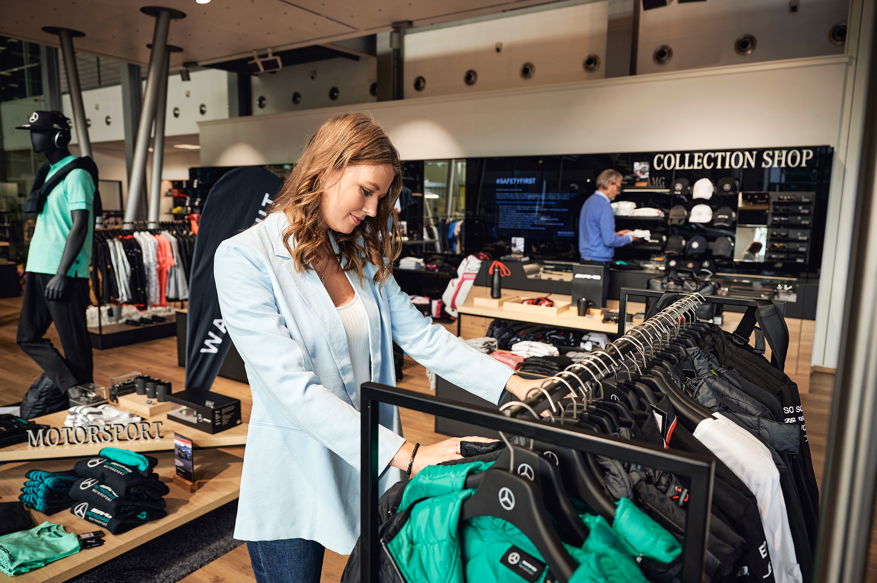 Eine Frau schaut sich Kleidung der Mercedes-Benz Collection in einem Kundencenter Shop an.